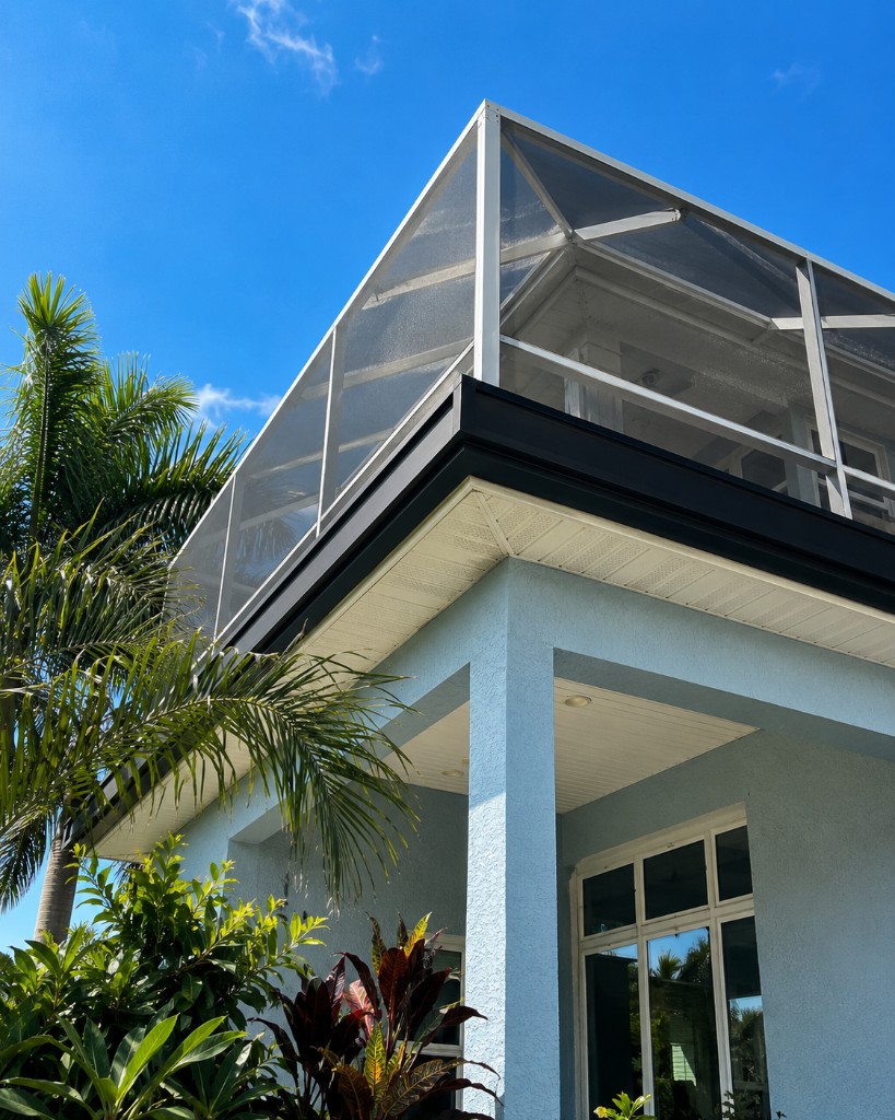 Super Gutter negra en una casa costera azul con screen enclosure en Tampa Bay