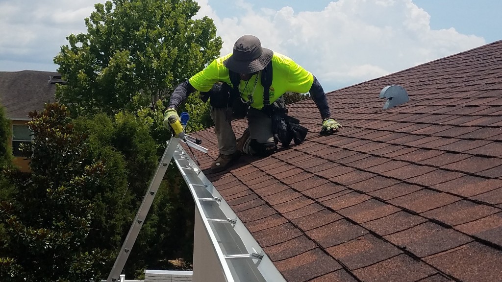 Professional gutter installation fastening hangers on a Tampa home