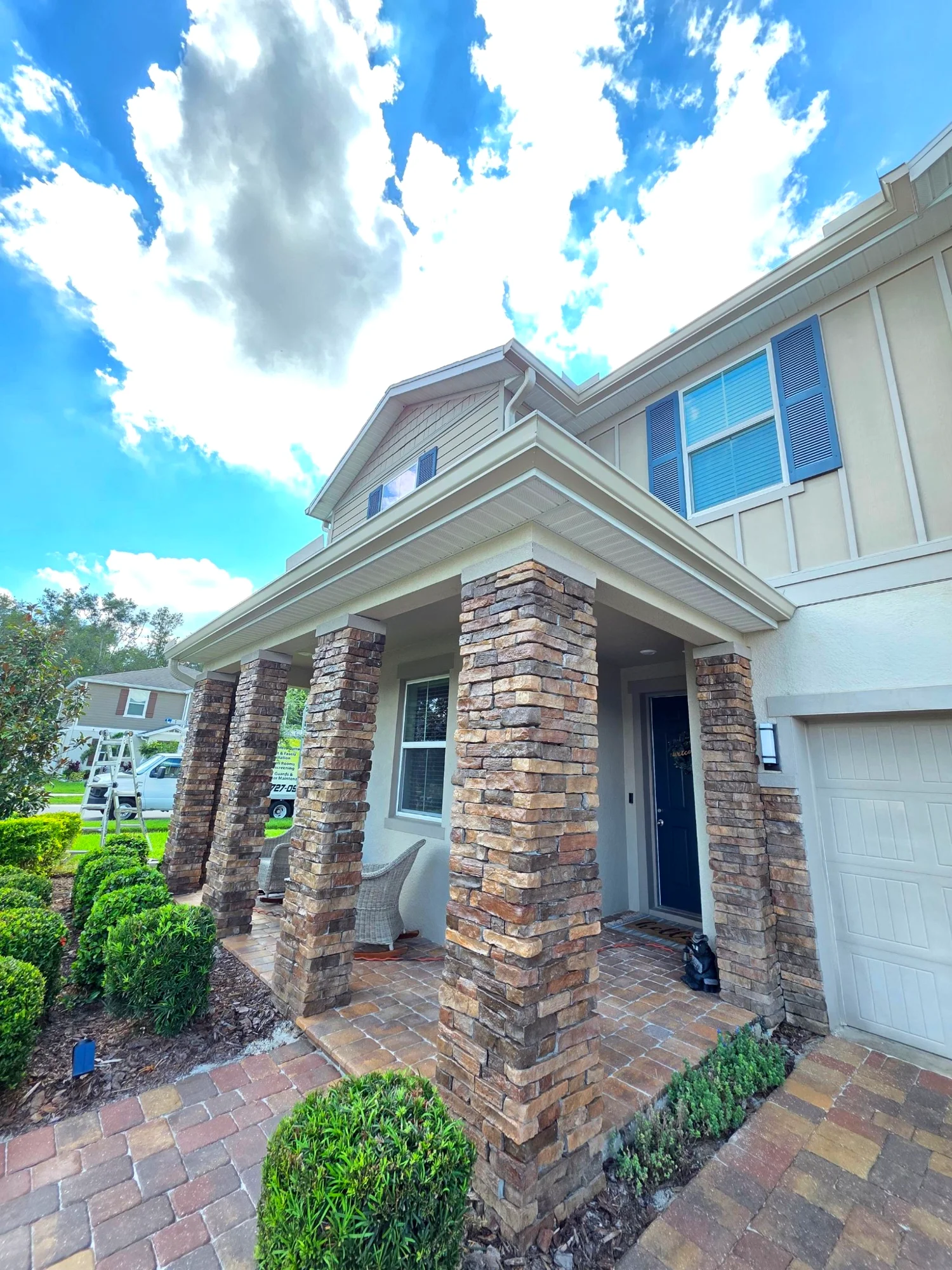 Copper-tone seamless gutters wrapping a Brandon front porch beneath mature oaks